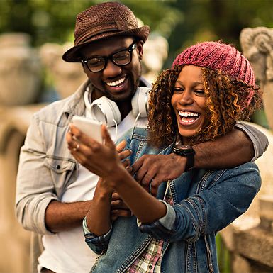 man and woman laughing looking at phone screen