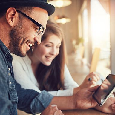 Young man and woman looking at a tablet in a cafe