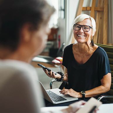 Two women in an office setting, one is smiling.
